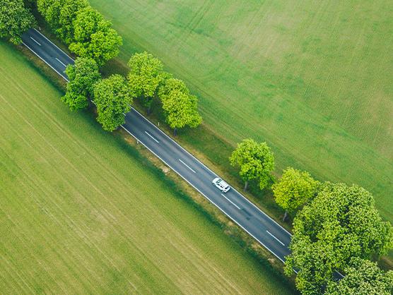 Mașină electrică pe un drum rural cu vegetație de ambele părți, ilustrând avantajele mobilității electrice