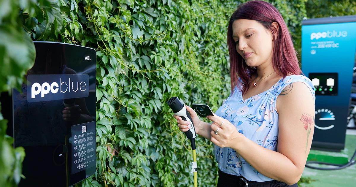 Femeie care verifică aplicația PPC blue înainte de încărcarea mașinii electrice